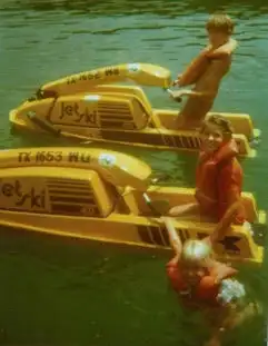 A man and a child are sitting on a yellow jet ski in the water.