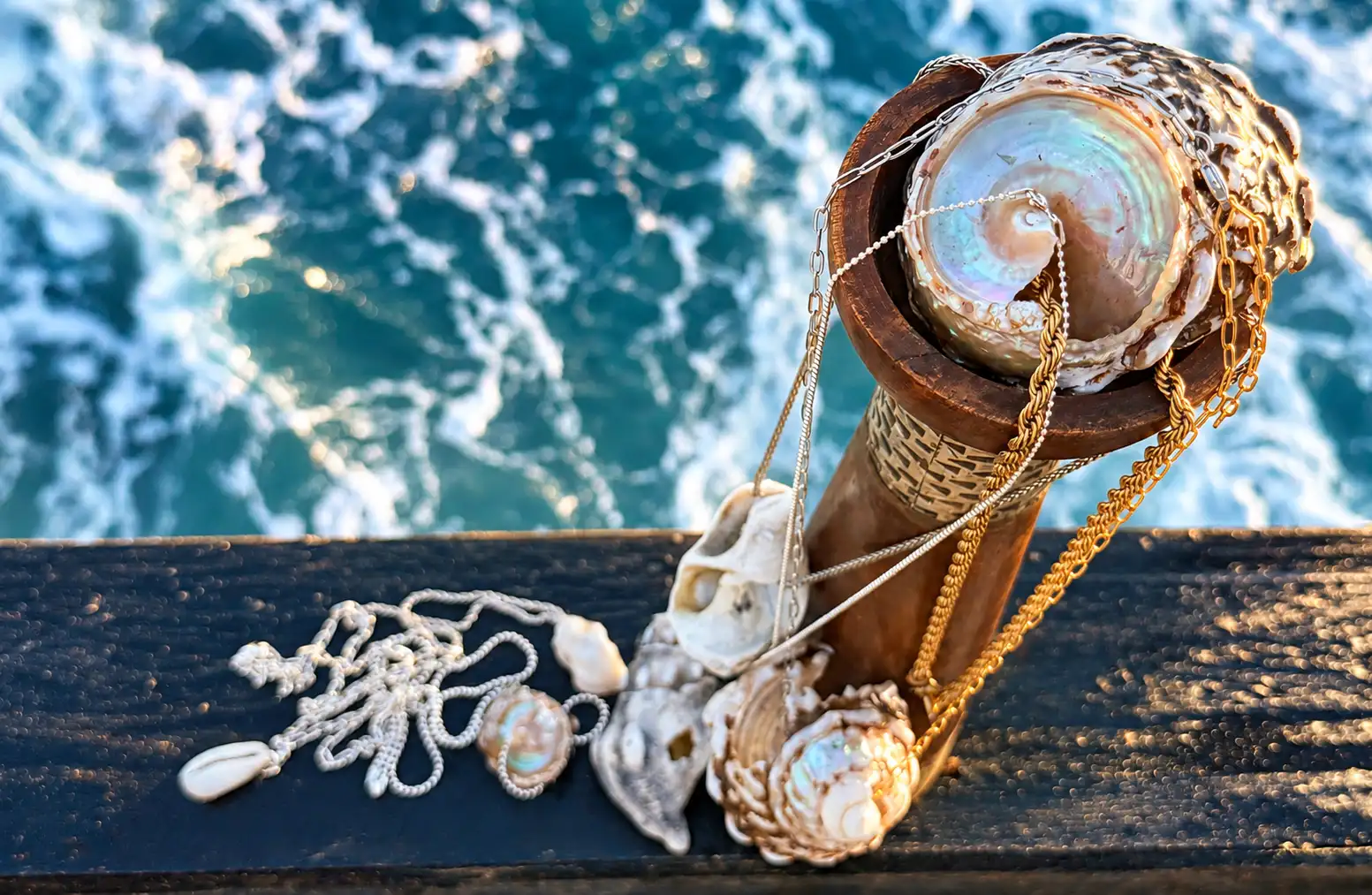 A wooden post with a shell necklace and a pearl necklace hanging from it.